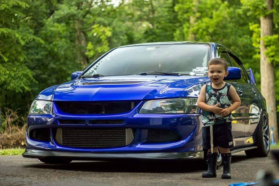 Young child standing beside a blue car