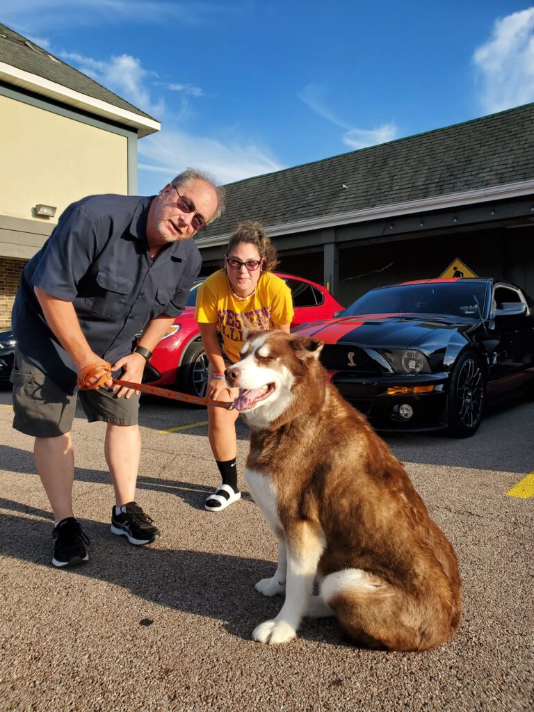 ChapterDrive community members with a dog beside parked cars
